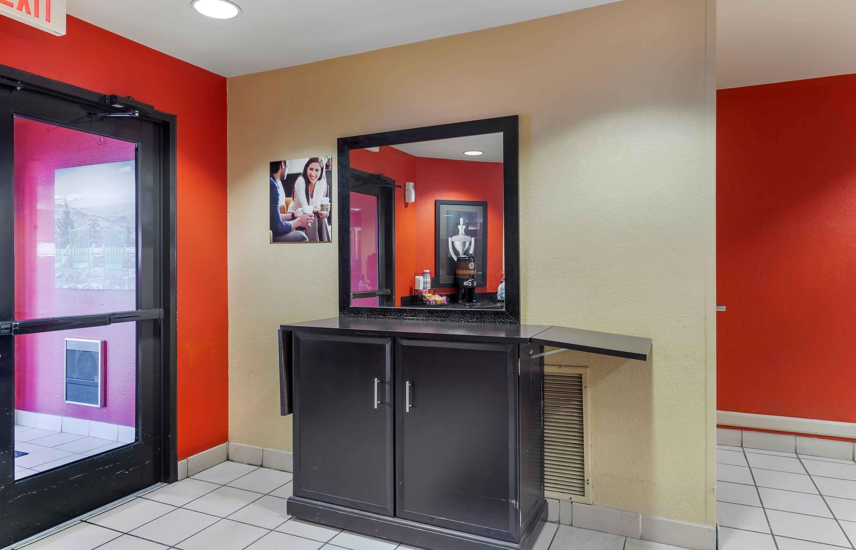 A hotel lobby with a reception desk, a mirror, and a framed picture on the wall.