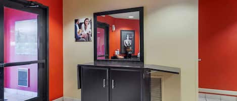 A hotel lobby with a reception desk, a mirror, and a framed picture on the wall.