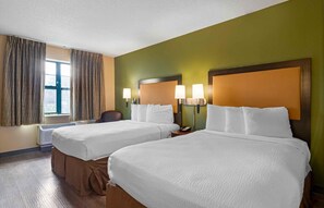 Habitación de hotel con dos camas, una ventana con cortinas, un calefactor en la pared y un teléfono en la mesita de noche.