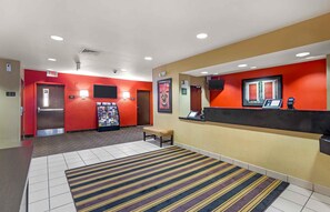 A hotel lobby with a reception desk, a bench, a vending machine, and a wall-mounted television. - Extended Stay America Suites Savannah Midtown (Savannah)