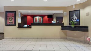 A hotel reception area with a reception desk, a framed picture of a trophy, and an exit sign. - Extended Stay America Suites Stockton March Lane (Stockton)