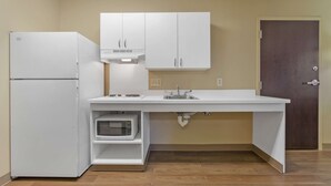 A compact kitchen with white cabinetry, a built-in microwave, and a sink. - Extended Stay America Suites Stockton March Lane (Stockton)