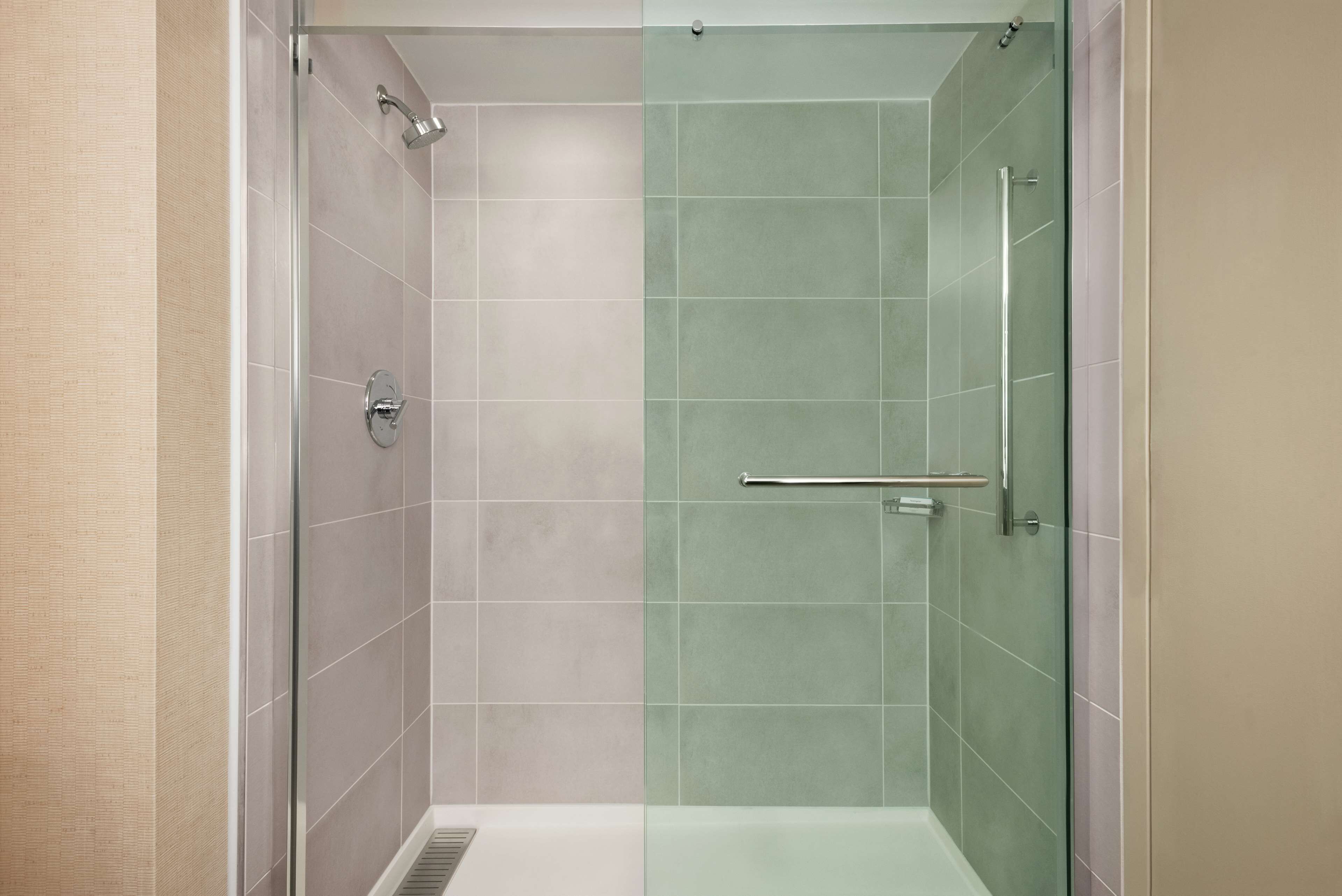 A glass-enclosed shower with a metal handle and a glass door.