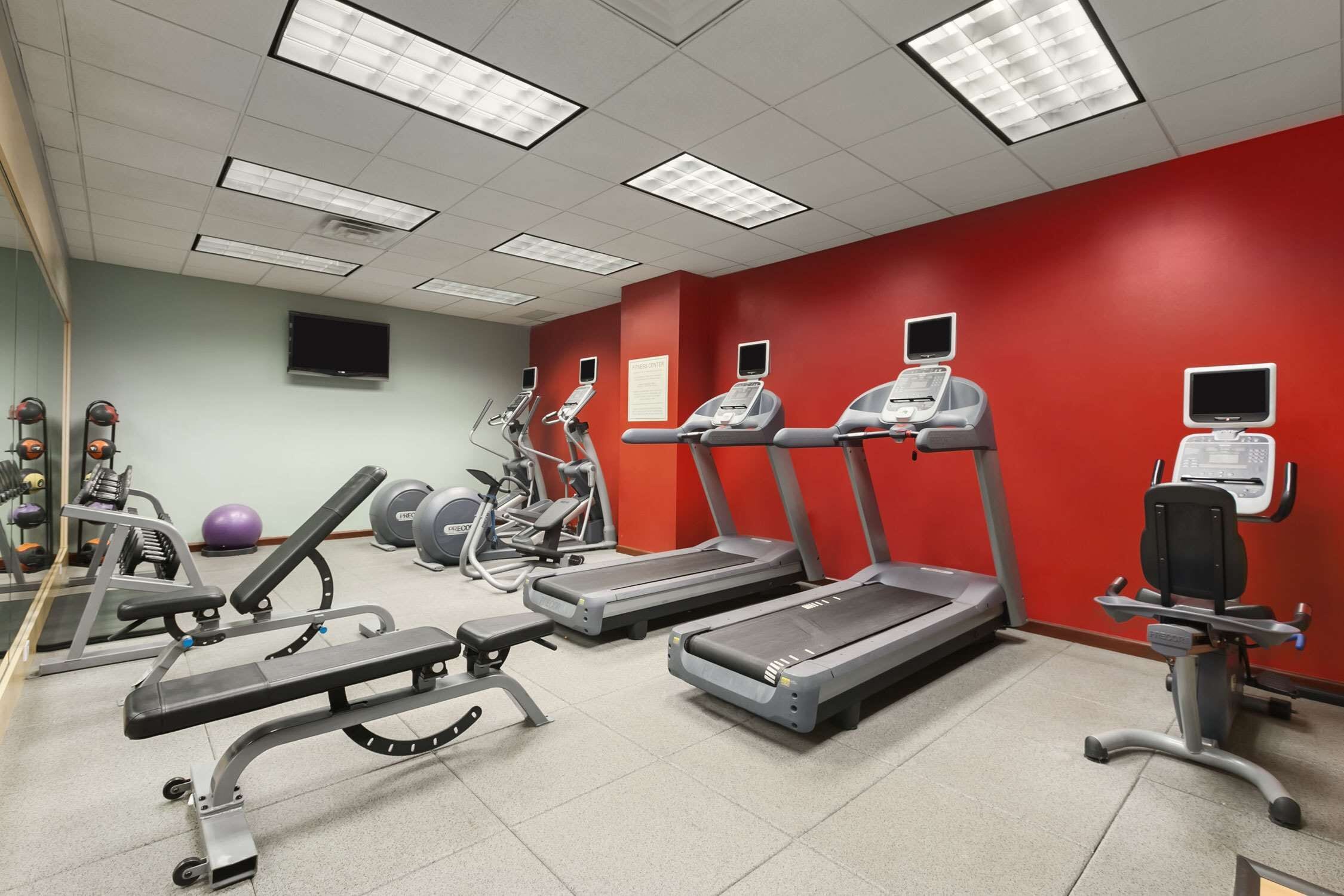 Un gimnasio con cintas de correr, elípticas y bancos de pesas.