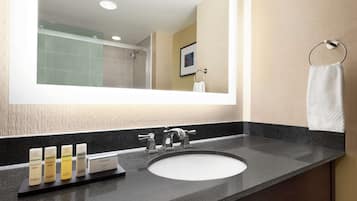 A bathroom with a large mirror, a sink, and a towel rack.