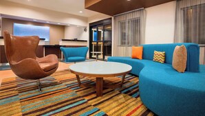Una sala de estar moderna con un sillón de cuero marrón, un sofá azul y una mesa de centro redonda.