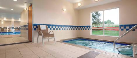 Une piscine bordée de carreaux bleus, une chaise et une fenêtre donnant sur un paysage verdoyant.