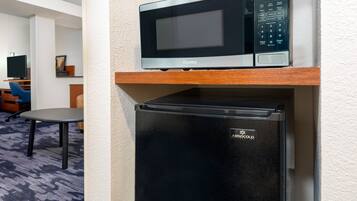 A compact kitchen area with a microwave and a black refrigerator.