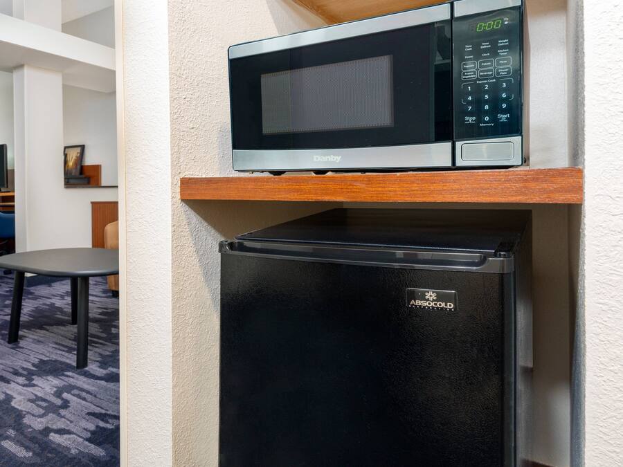 A compact kitchen area with a microwave and a black refrigerator.