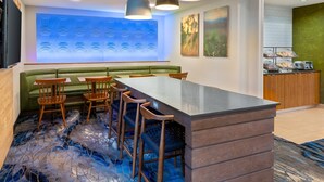 Zona de bar moderna con una barra larga, taburetes y lámparas colgantes.