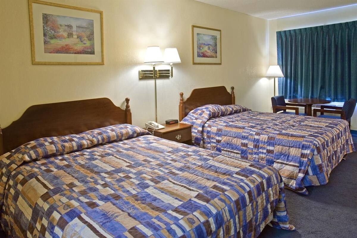 A hotel room with two beds, a desk, and a chair.