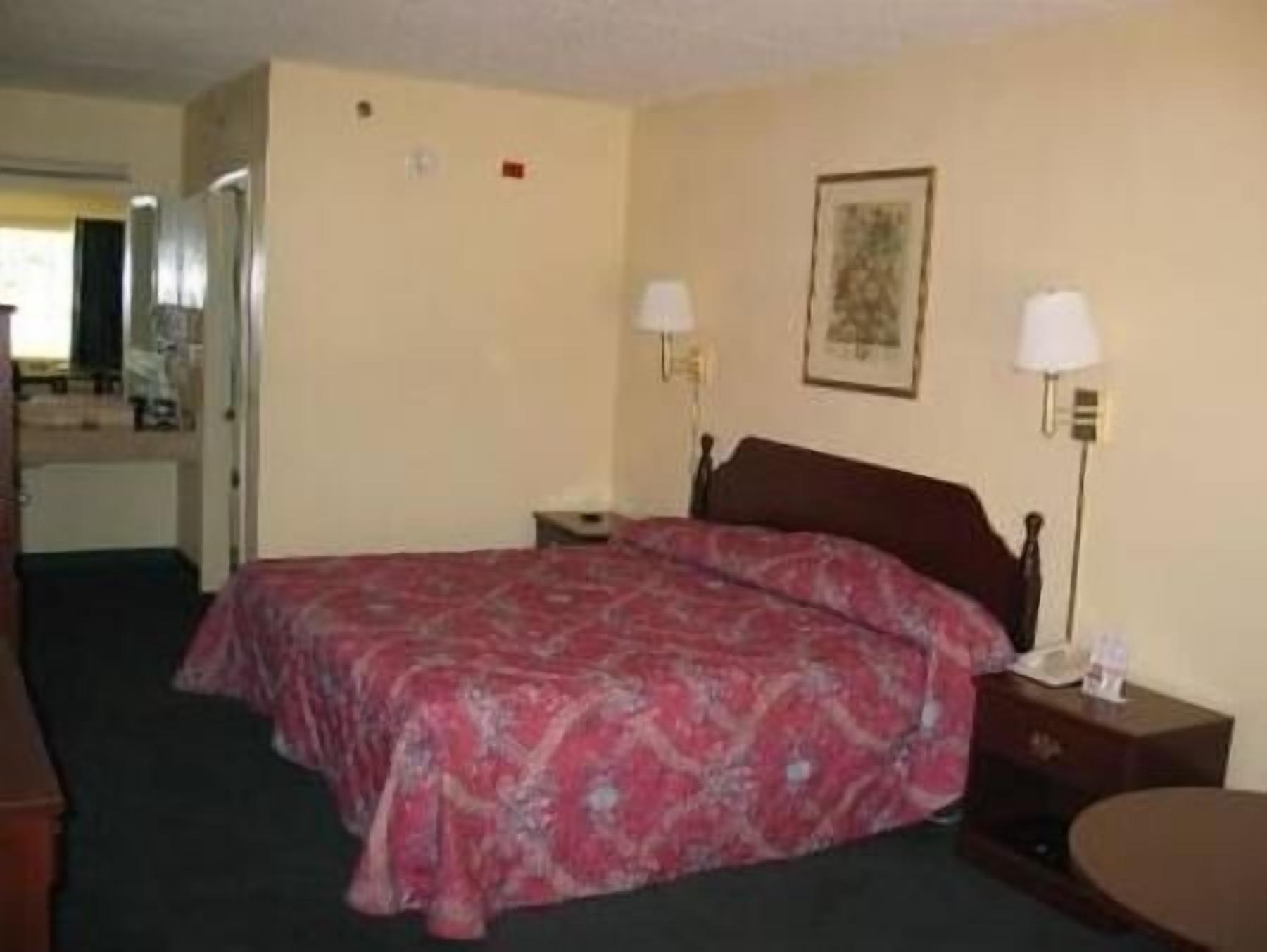 A hotel room with a bed, bedside tables, a desk, and a chair.