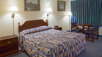 Una habitación de hotel con una cama grande, dos mesitas de noche, un escritorio con una silla y dos lámparas de pared.