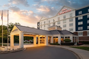 A hotel entrance with a covered waiting area, a clear sky, and a flagpole. - Hilton Garden Inn Rock Hill (Rock Hill)