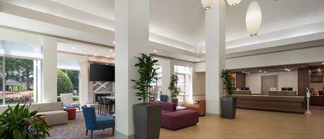 A spacious lobby with a reception desk, seating areas, and large windows.