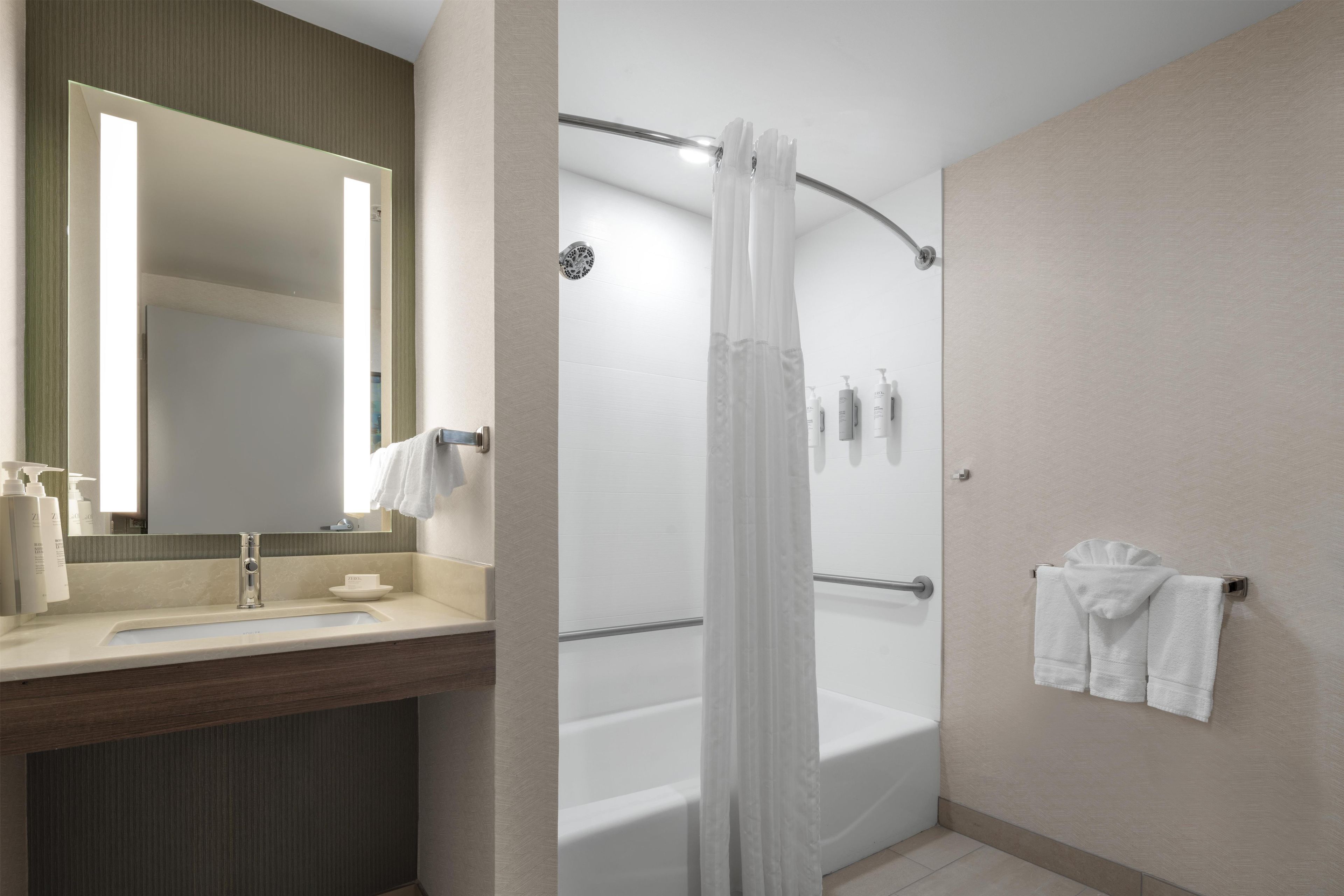 Un baño moderno con un espejo grande, una bañera y una zona de ducha.