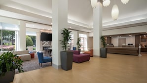 A spacious lobby with a reception desk, seating areas, and large windows offering views of the outdoors.