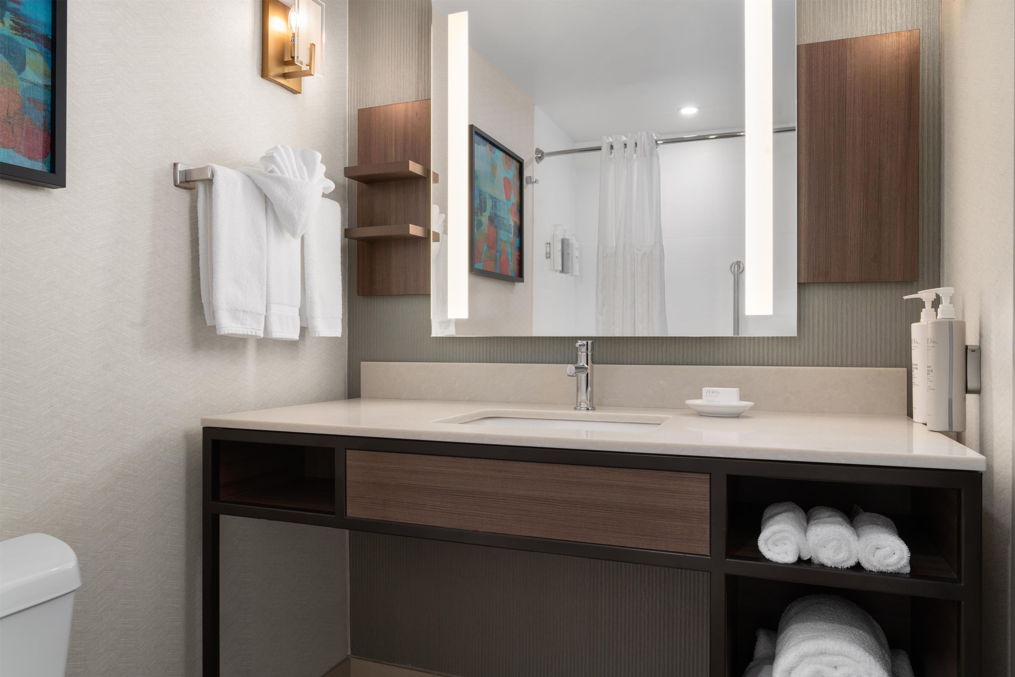 Un baño moderno con un espejo grande, un lavamanos y un perchero para toallas.