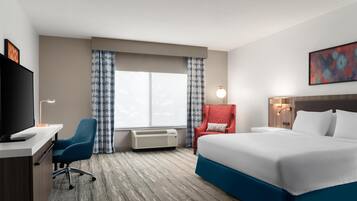 Ein Hotelzimmer mit Bett, Schreibtisch, Stuhl, Klimaanlage und Fernseher.