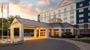 A hotel entrance with a covered area, a clear sky, and an American flag.