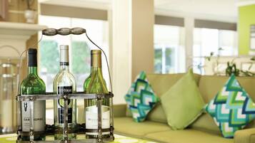 Una botellera con botellas sobre una mesa en una habitación con un sofá y cojines estampados.