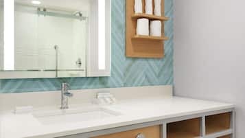 A modern bathroom with a white sink, a mirror, and a wooden shelf with toiletries.