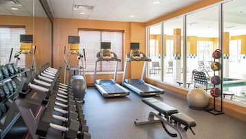 A gym with treadmills, dumbbells, and exercise balls.