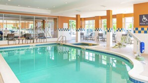 An indoor swimming pool with clear water, surrounded by lounge chairs and a pool lift.