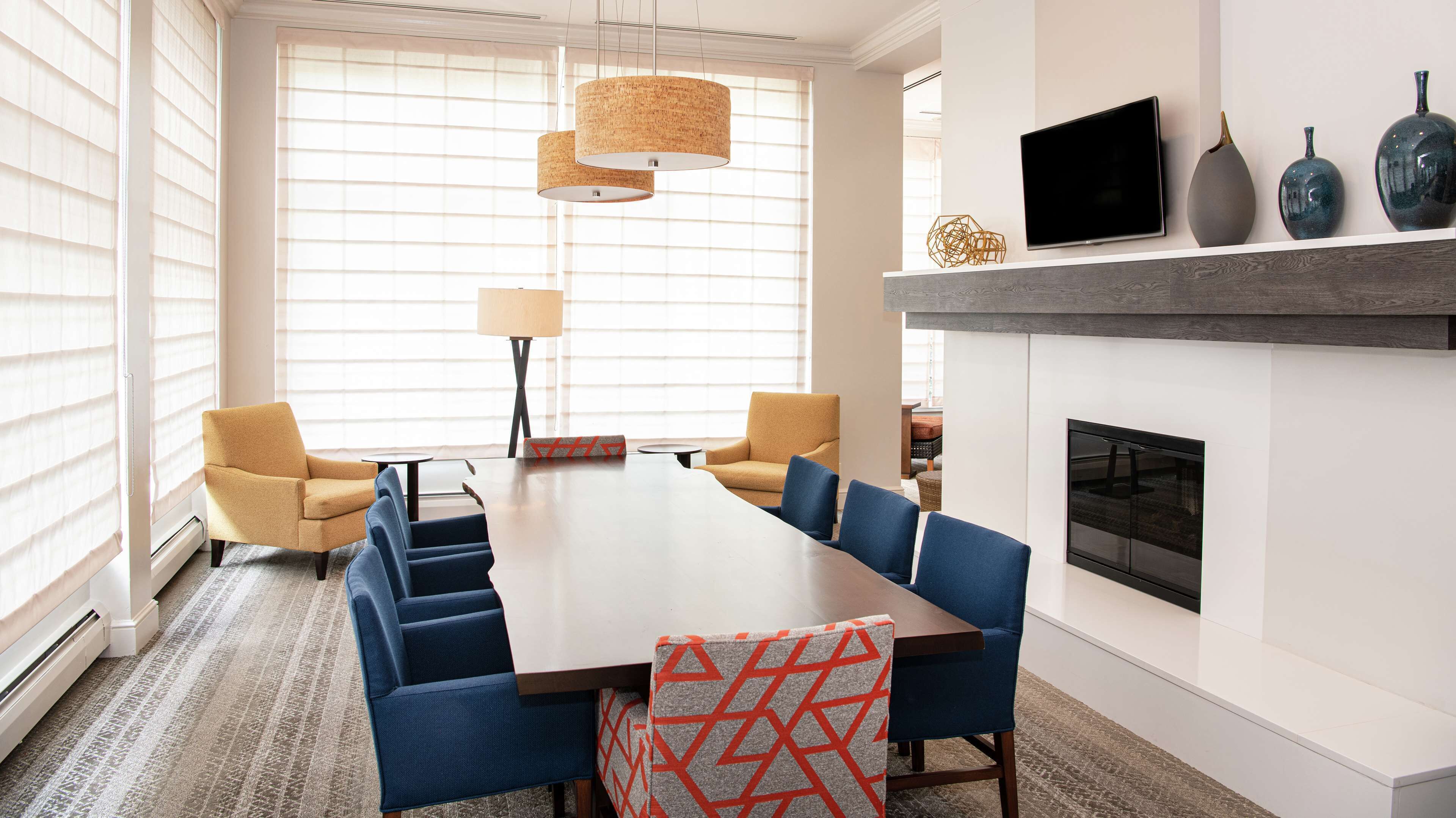Un comedor moderno con una mesa larga, sillas tapizadas en azul y una chimenea.