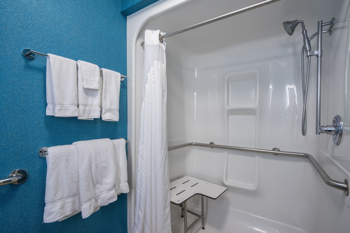 A bathroom with a bathtub, shower, and a white towel rack.