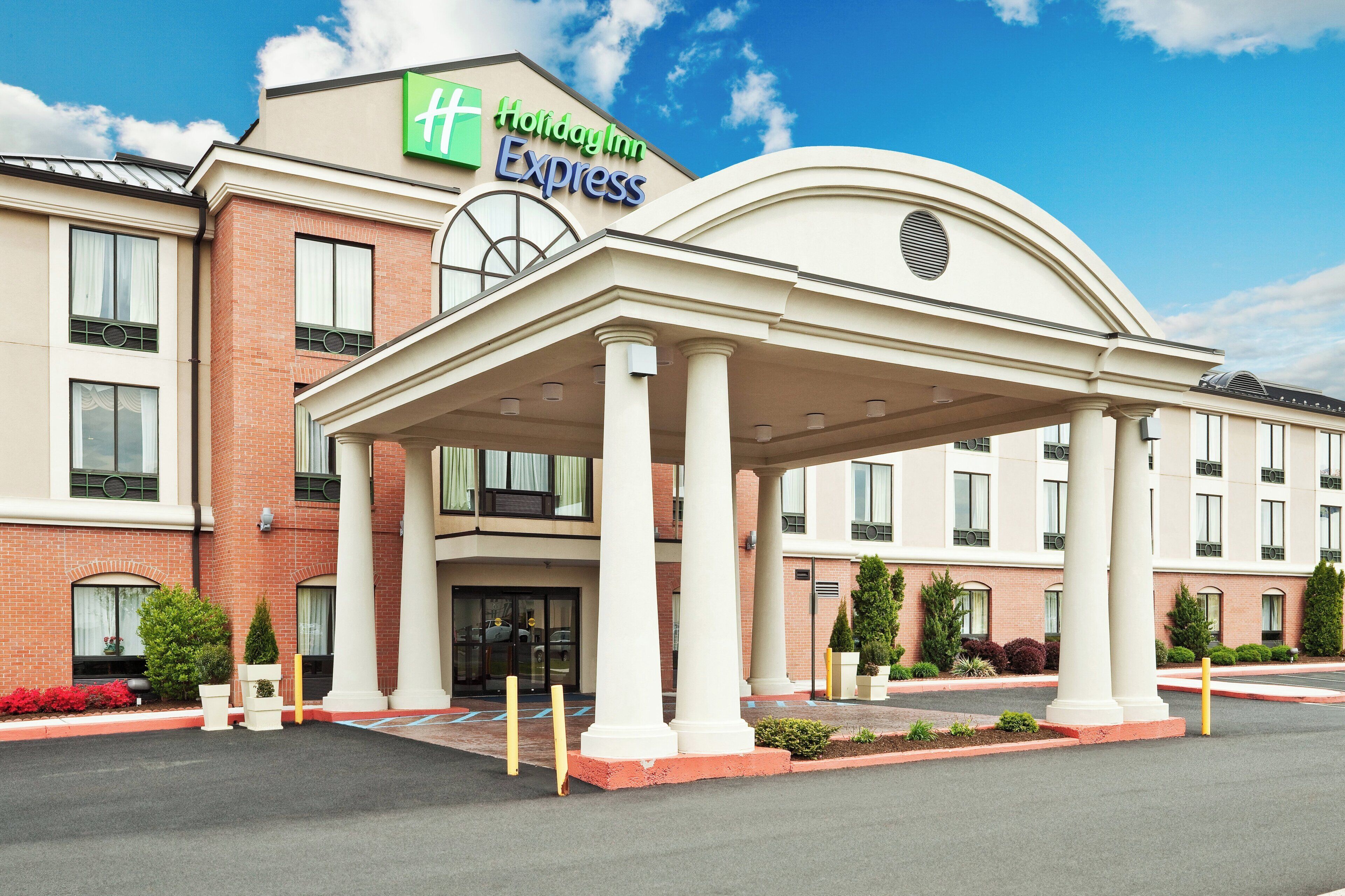 Un hôtel Holiday Inn Express doté d’une entrée abritée, d’une façade en briques et de nombreuses fenêtres.