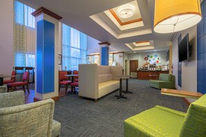 A hotel lobby with seating areas, a reception desk, and a bar.