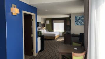 Habitación de hotel con cama, escritorio, silla y un amplio ventanal.