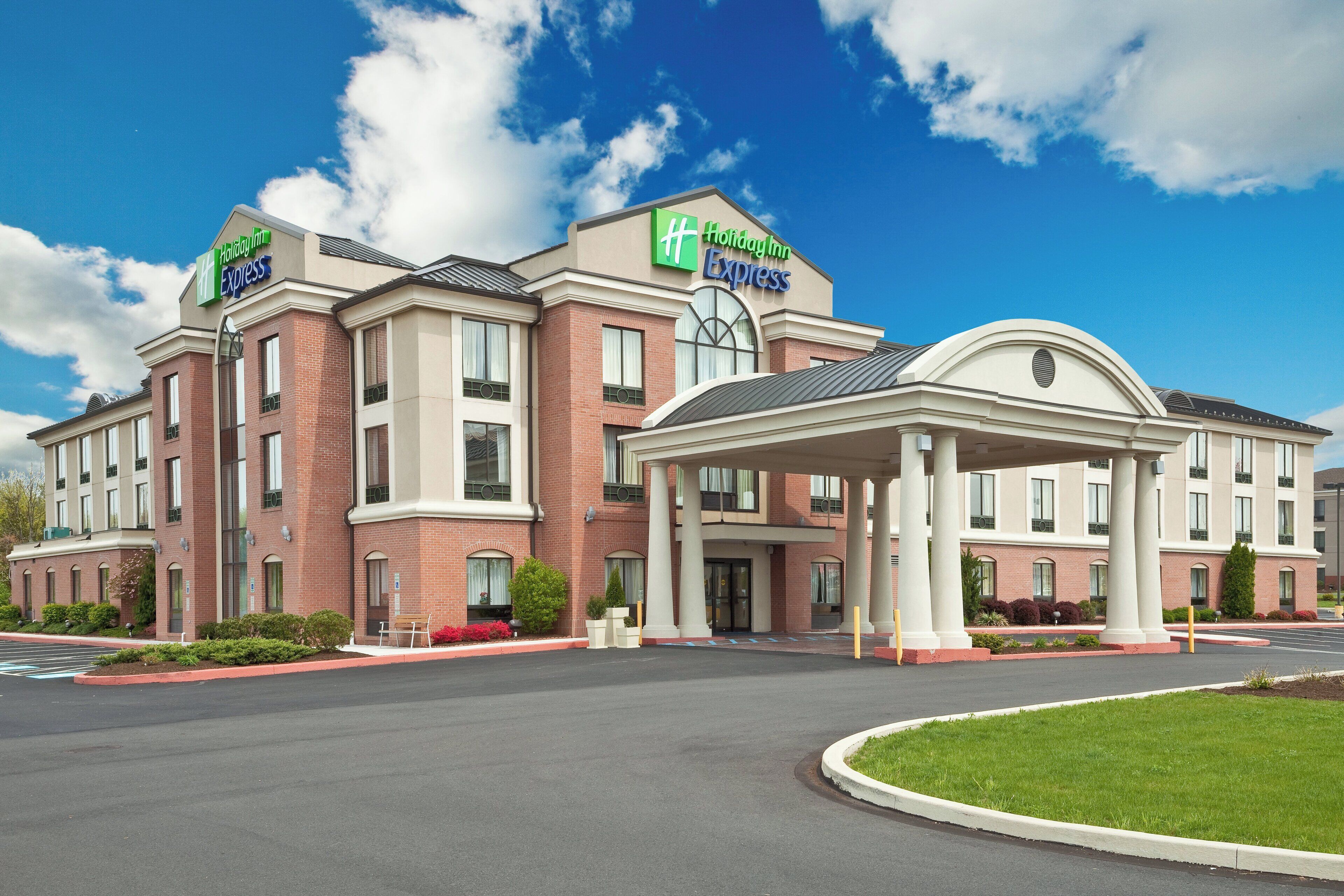 Un hôtel Holiday Inn Express avec une façade en briques, une entrée couverte et un parking.