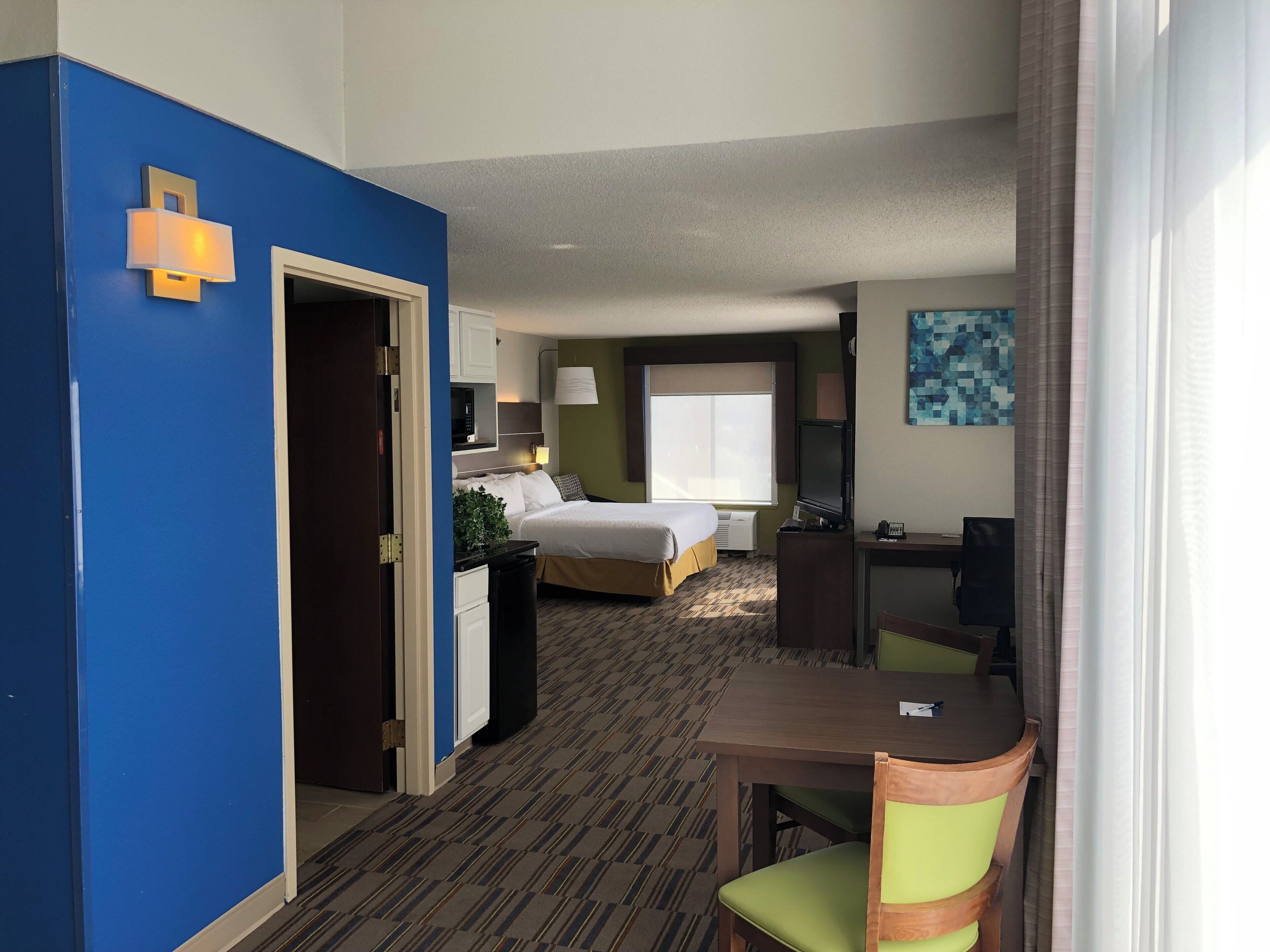 Une chambre d’hôtel avec un lit, un bureau, une chaise et une fenêtre.