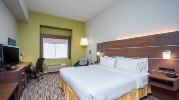 Una habitación de hotel con una cama grande, un escritorio con computadora, una silla y un televisor.