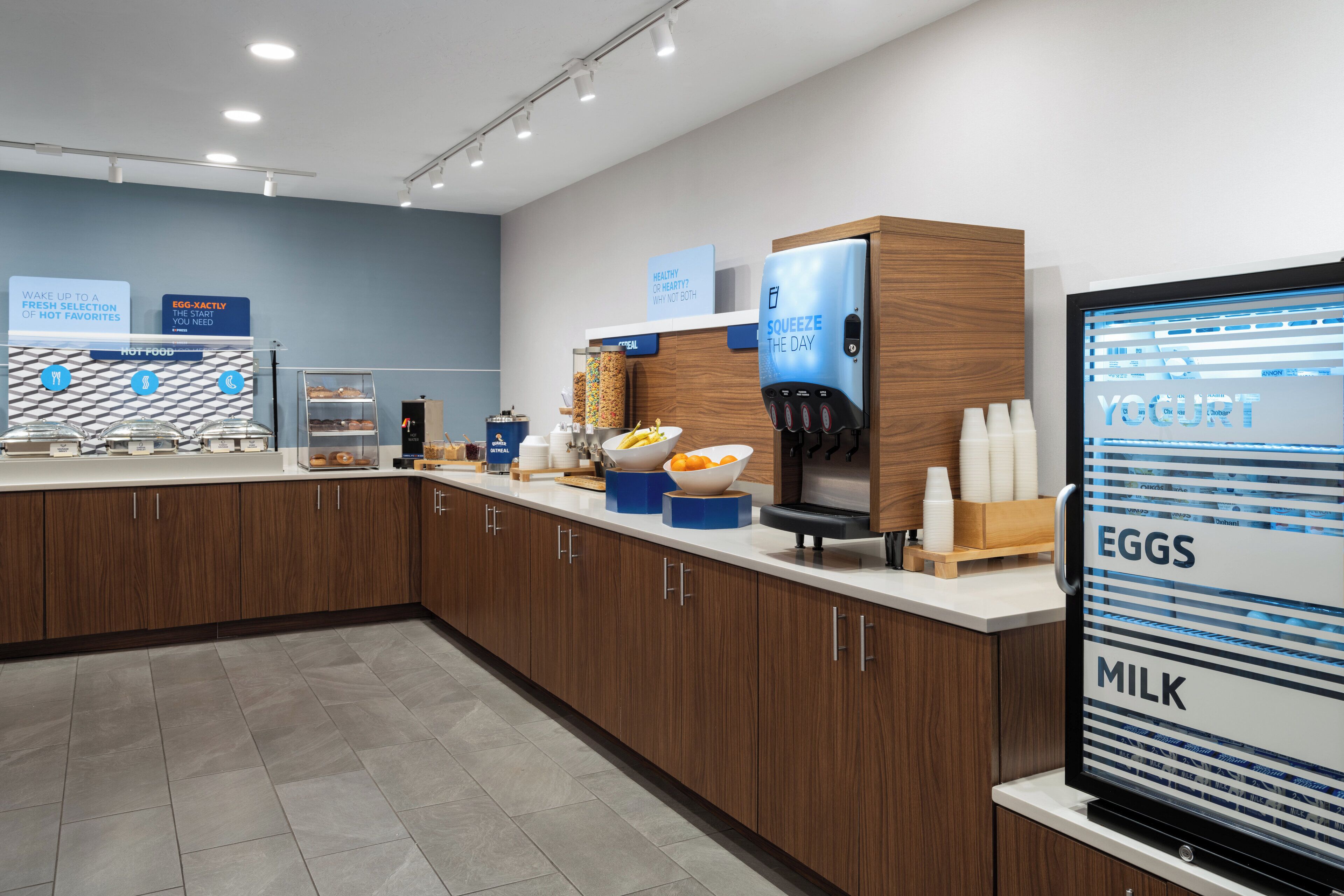A modern breakfast area with a yogurt dispenser, a coffee machine, and a sign for eggs and milk.