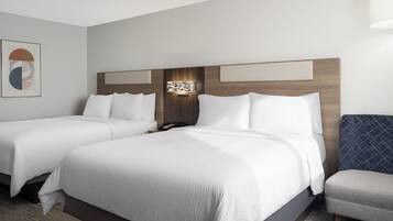 Ein Hotelzimmer mit zwei Betten, einem Nachttisch, einer Lampe und einem gerahmten Bild an der Wand.