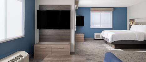 Una habitación de hotel moderna con un televisor de pantalla plana grande, una cama, un sofá y una mesita.