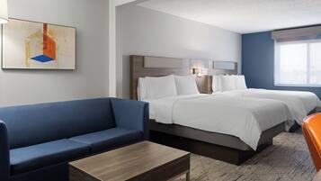 Ein Hotelzimmer mit einem Bett, einem blauen Sofa, einem Holztisch und einem Gemälde an der Wand.