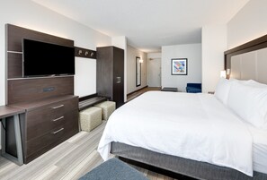 A modern hotel room with a large bed, a flat-screen TV, a desk with drawers, a wardrobe, and a small seating area. - Holiday Inn Express & Suites Dublin by IHG (Dublin)