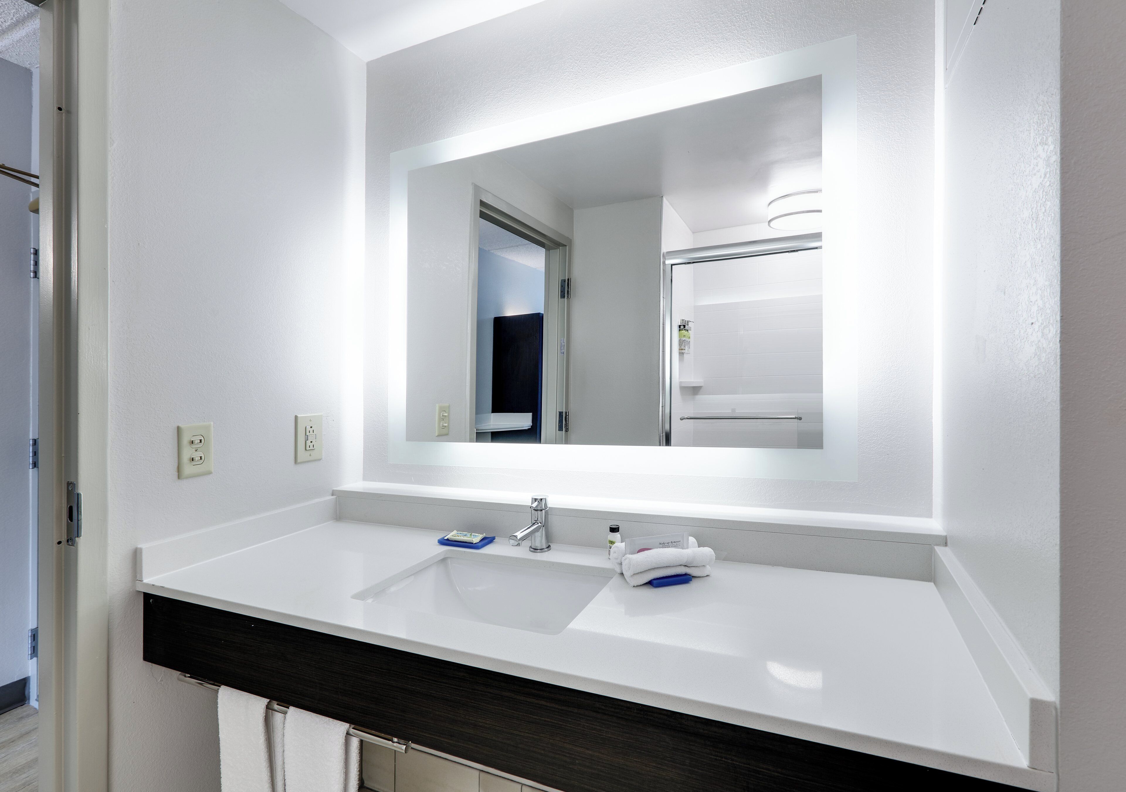 Une salle de bain moderne avec un lavabo blanc, un miroir et un meuble-lavabo en bois foncé.