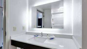Une salle de bain moderne avec un lavabo blanc, un miroir et un meuble-lavabo en bois foncé.