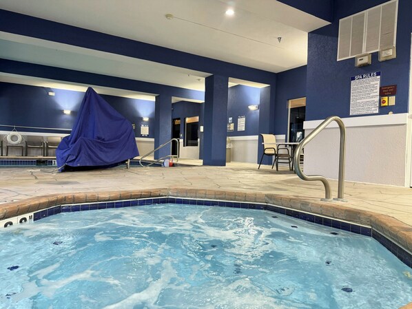 Un espace autour de la piscine comprenant un banc couvert, une chaise et un panneau indiquant les règles à respecter.