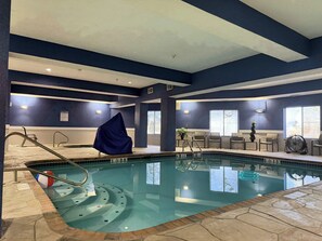 Une piscine intérieure avec des marquages bien visibles, un espace abrité et des sièges placés près des fenêtres.