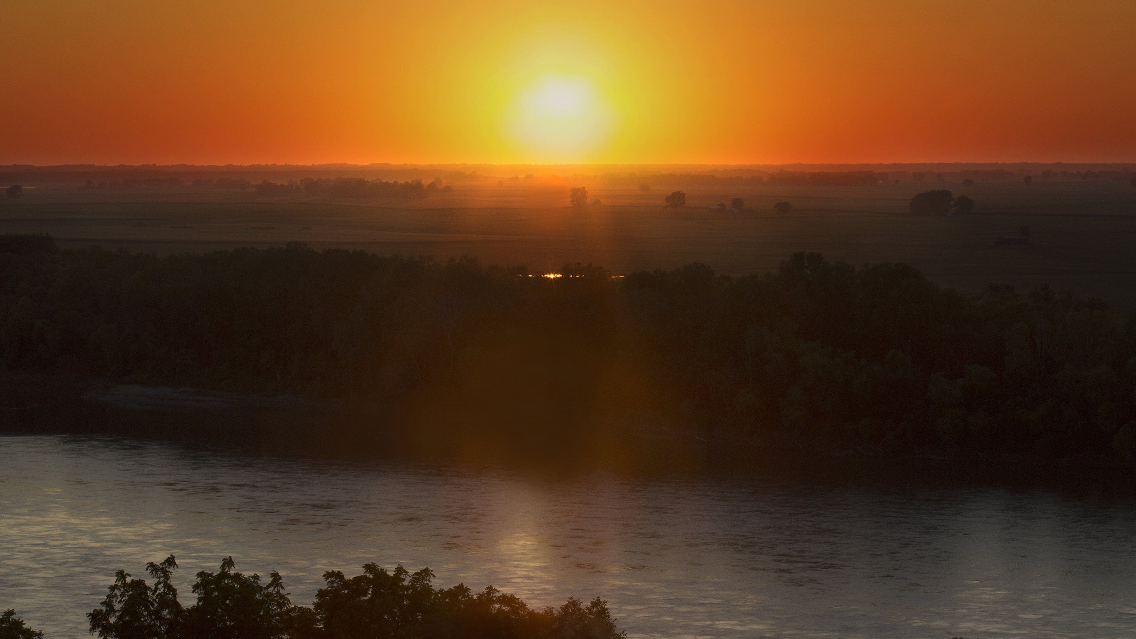 Un atardecer sobre un río, con una vista distante del horizonte urbano.