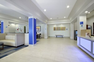 A spacious lobby with a reception desk, seating area, and artwork on the walls.