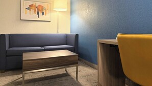 A modern room with a blue wall, a gray sofa, a wooden coffee table, and a yellow chair. - Holiday Inn Express Boonville by IHG (Boonville)