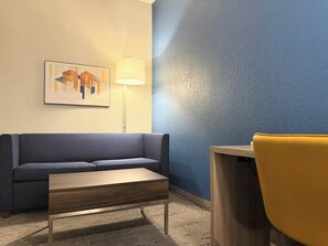 Une pièce moderne avec un mur bleu, un canapé gris, une table basse en bois et une chaise jaune.