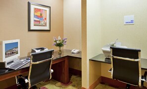 Une chambre d’hôtel équipée d’un bureau, de deux chaises, d’une imprimante, d’un téléphone, d’un tableau et d’un panneau « Interdiction de fumer ».